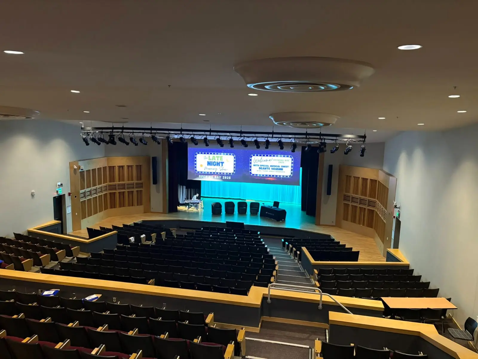 Auditorium stage with a wide LED wall and a truss of theatrical fixtures