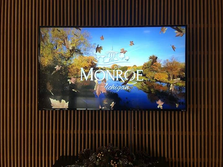 Wall-mounted digital signage display showing a City of Monroe welcome screen