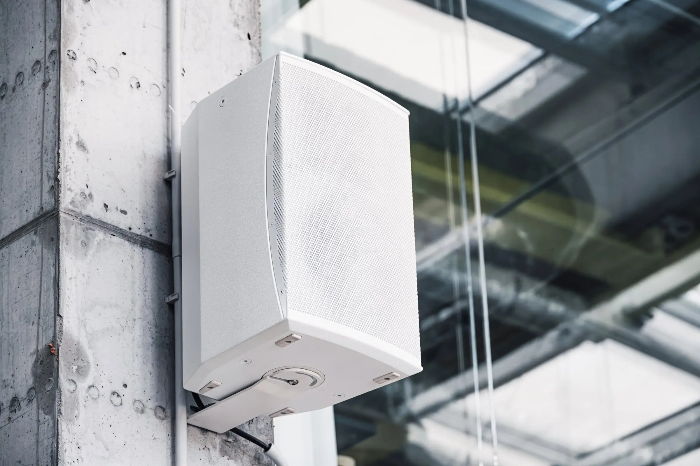White wall-mounted loudspeaker on a concrete column